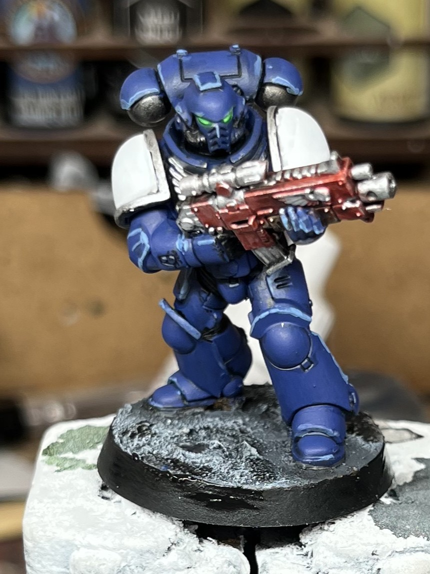 Photograph of a set of 5 28mm space marine. One of the models is painted and the other 4 are grey plastic.