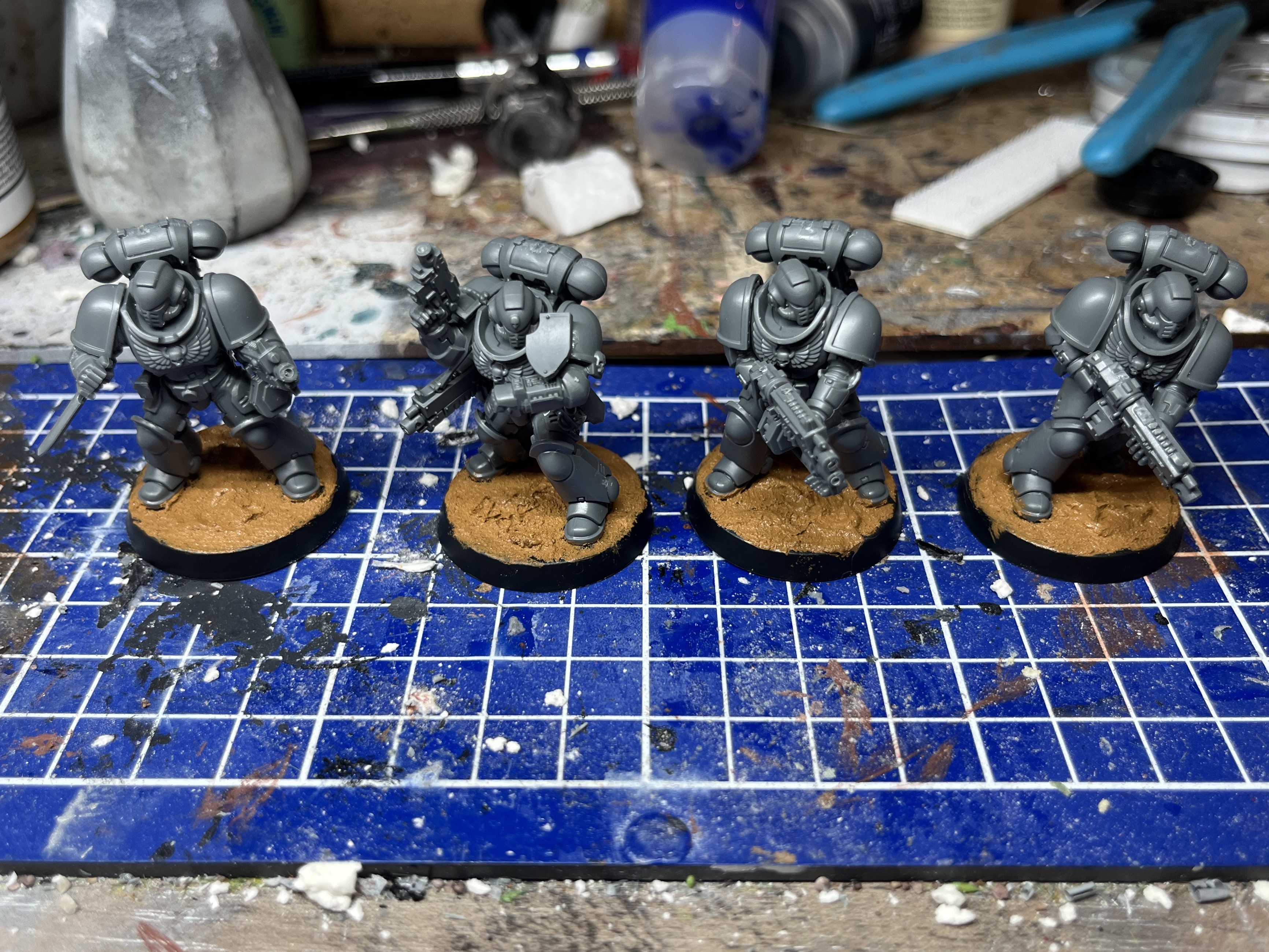 Photograph of a set of 5 28mm space marine. One of the models is painted and the other 4 are grey plastic.
